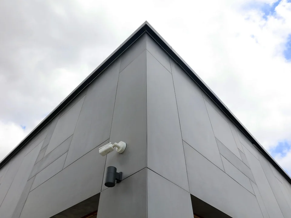 Upward architectural corner view of smooth grey through-coloured fibre cement rainscreen panels with crisp open joints