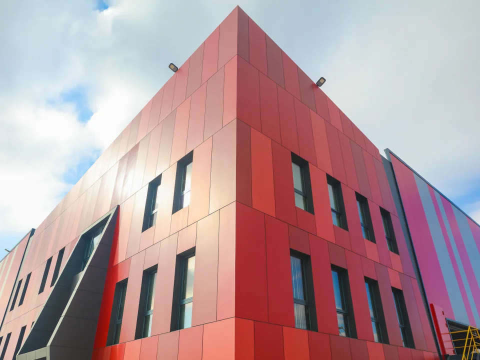 Modern industrial corporate building clad in vibrant red painted fibre cement panels with sharp geometric joint grid