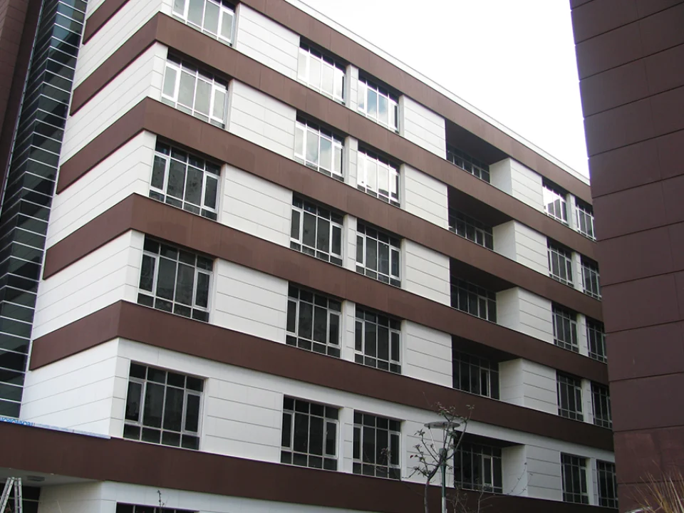 Six-storey urban apartment building clad in alternating crisp white window piers and continuous earth-brown horizontally grooved fibre cement spandrel bands