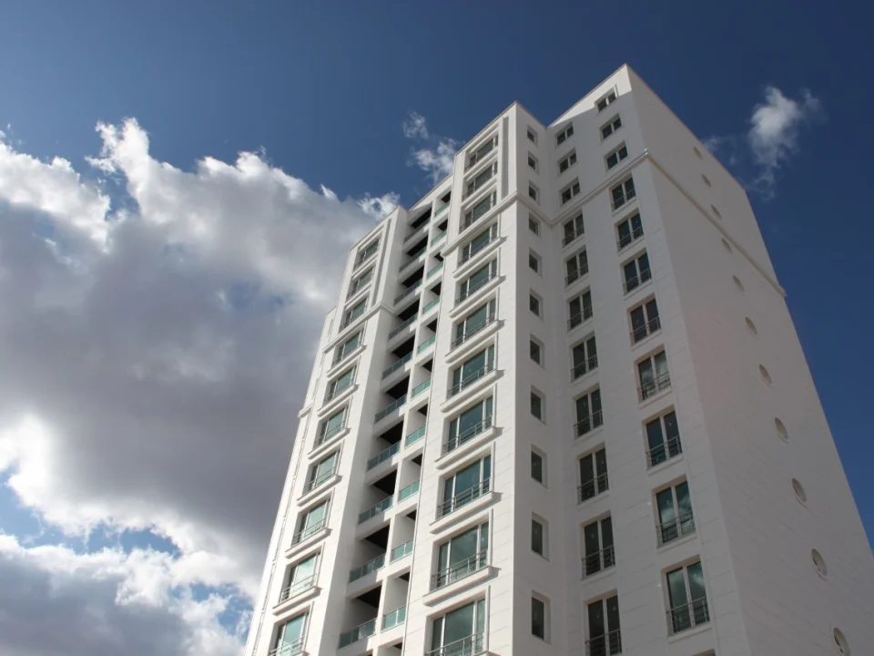 Upward perspective of white high-rise residential tower featuring 20 mm fibre cement window surrounds and grooved facade panels