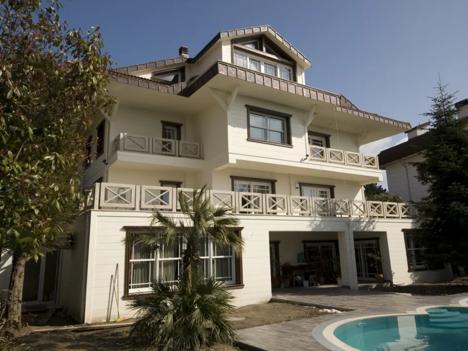 Large three-storey garden villa with swimming pool clad entirely in off-white painted horizontal fibre cement lap siding