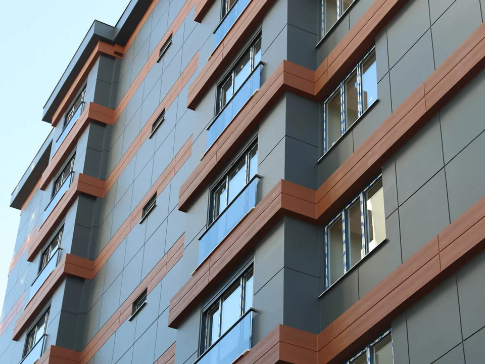 Close-up urban apartment facade clad in anthracite grey and warm terracotta painted smooth fibre cement panels