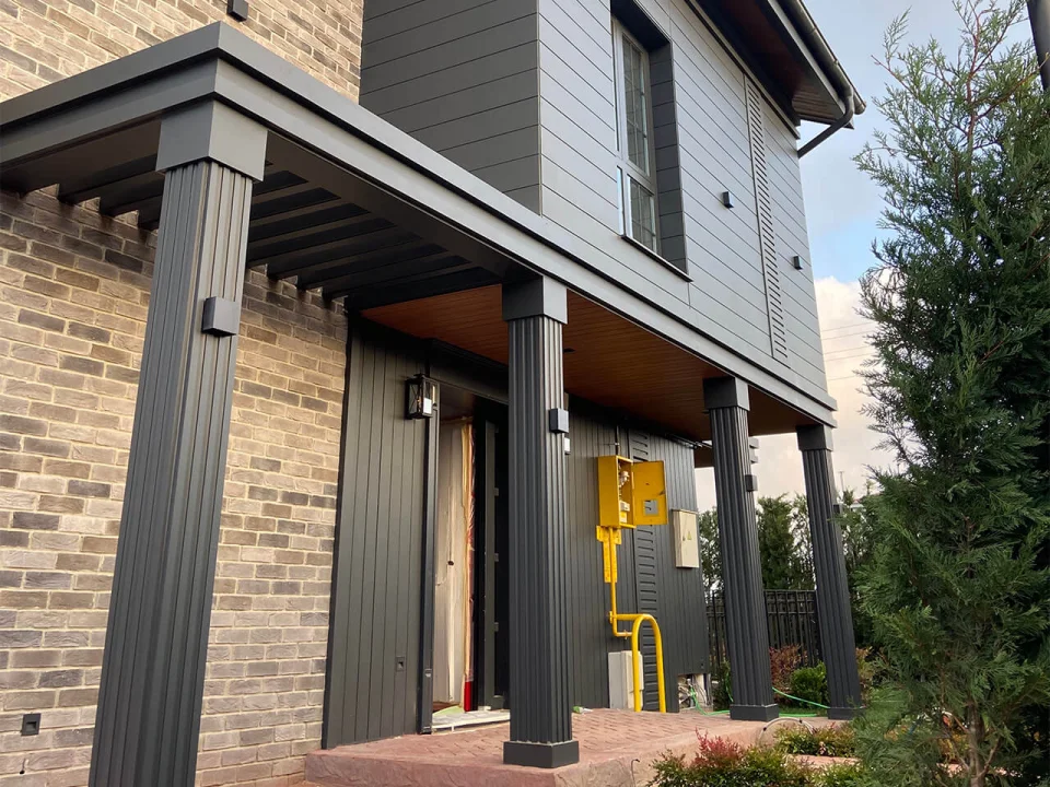 Modern villa porch combining earth-toned staggered brick-relief fibre cement boards on ground floor with charcoal upper facade panels
