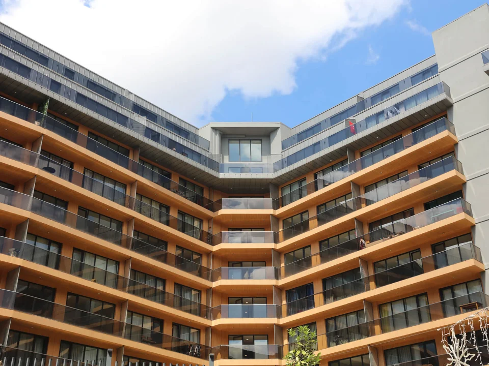 Curved multi-storey residential complex featuring warm timber-toned wood-textured fibre cement spandrel bands across every floor