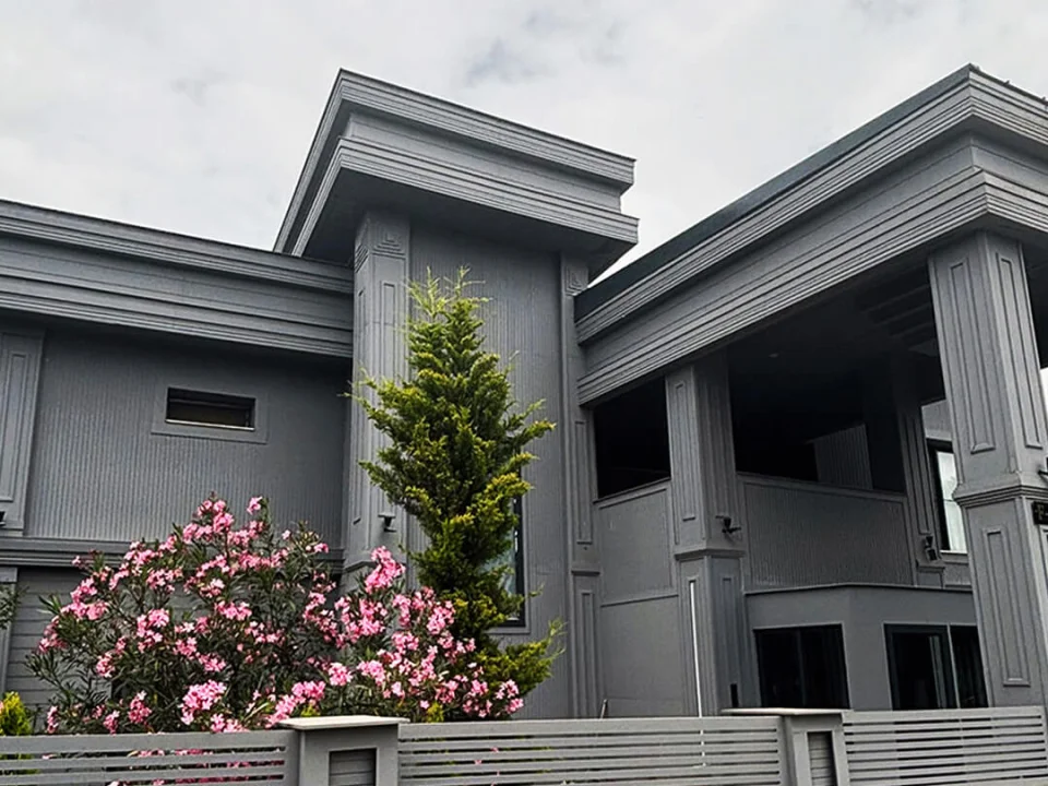 Monumental villa entrance clad in dark grey decorative stone-textured fibre cement panels, fluted pilasters and cornice trims