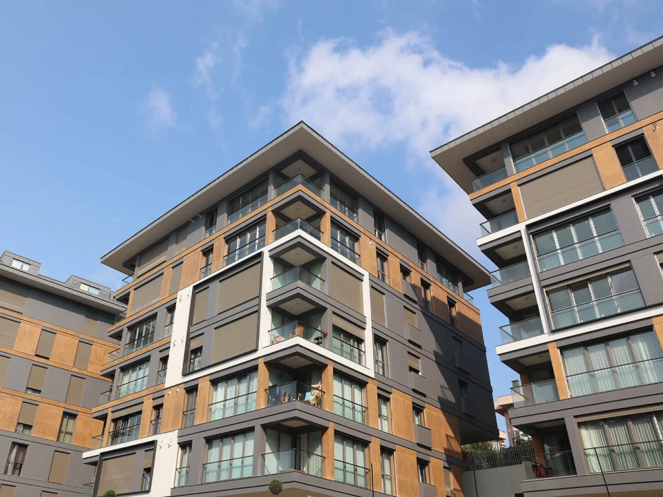 Contemporary multi-block residential estate clad in charcoal grey striped fibre cement panels and warm timber-toned accent bays