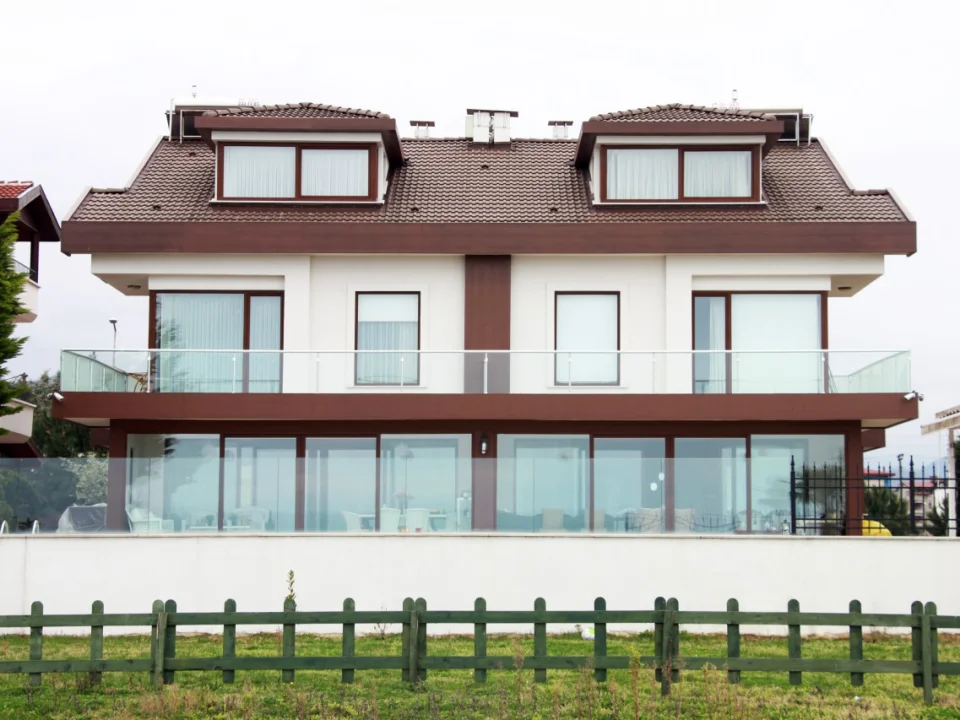 Detached two-storey residence featuring crisp white fibre cement wall cladding contrasted with dark brown fascia and balcony bands